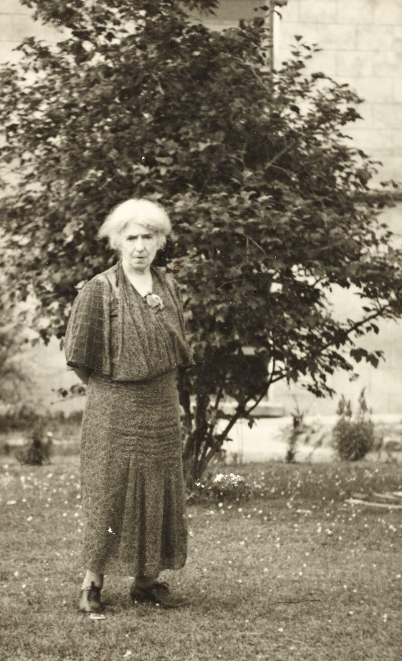 [Áine Ceannt, standing outdoors near tree, full-length portrait