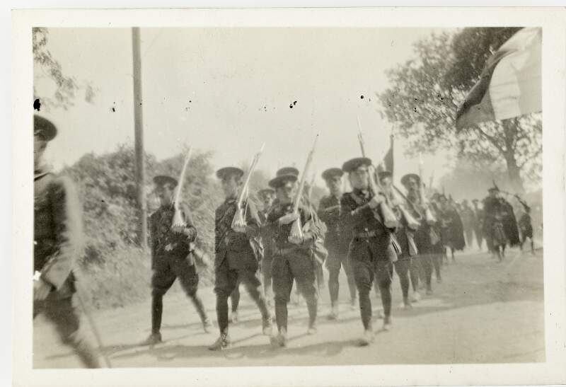 [Unidentified men holding guns marching along country road, with tricolour visible]