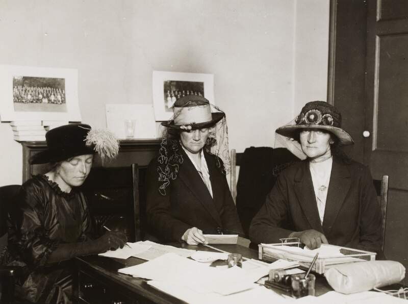[Muriel MacSwiney, Mary MacSwiney and an unidentified woman sitting at a desk]