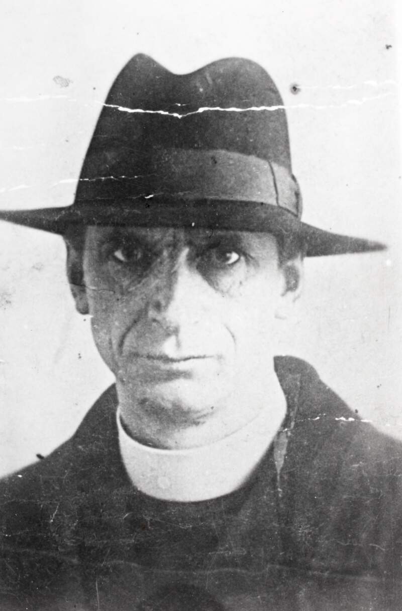 [Éamon De Valera, dressed in a clerical collar and wearing a hat, front facing, head and shoulder length portrait]