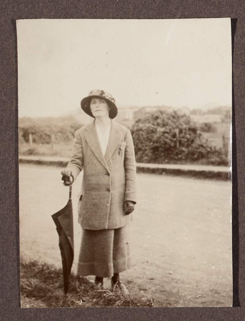 [Unidentified woman, standing by the roadside holding an umbrella]