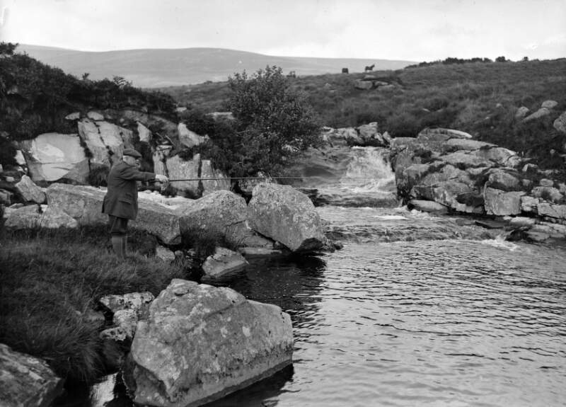 [John Redmond fishing, along rocky banks of a river]