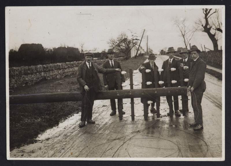 [Group of men posing with the telegraph pole, forming part of the Dublin-Belfast line, which was felled by the I. R. A.]
