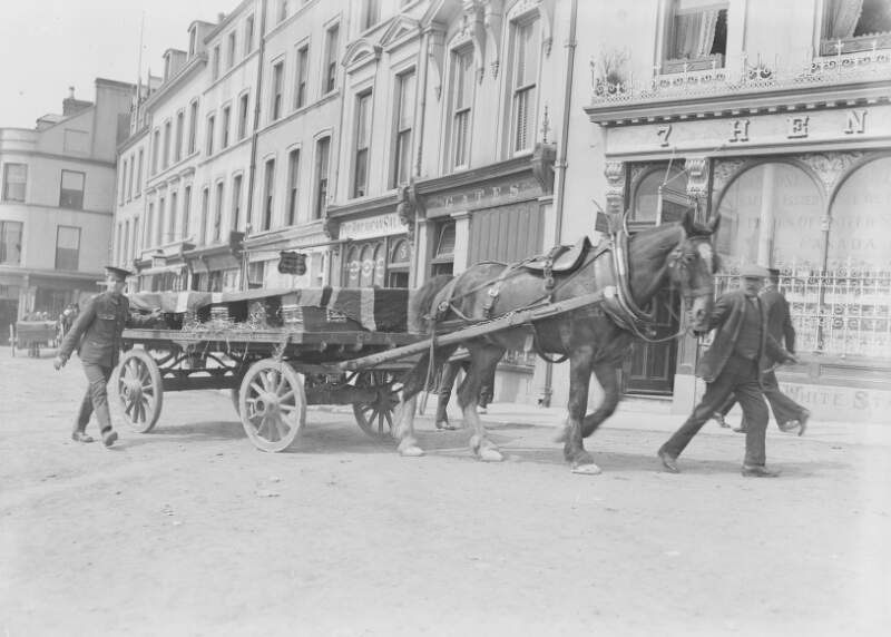 [Lusitania disaster, Cobh, Co. Cork : coffin draped in flag drawn by horse and cart, with soldier walking alongside]