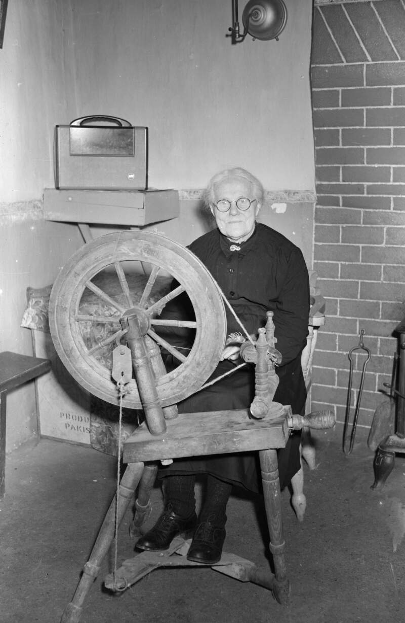 [Elderly woman at a spinning wheel in a thatched cottage near Ardara, Co. Donegal]
