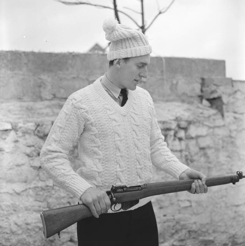 [Male modelling garments, with gun, for Dungloe Co-op knitting, Co. Donegal]