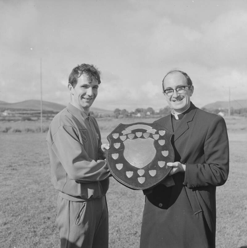 [Men holding plaque on football field, at Queen and Exiles Carnival, D'Alton Sports, Glenties, Co. Donegal]