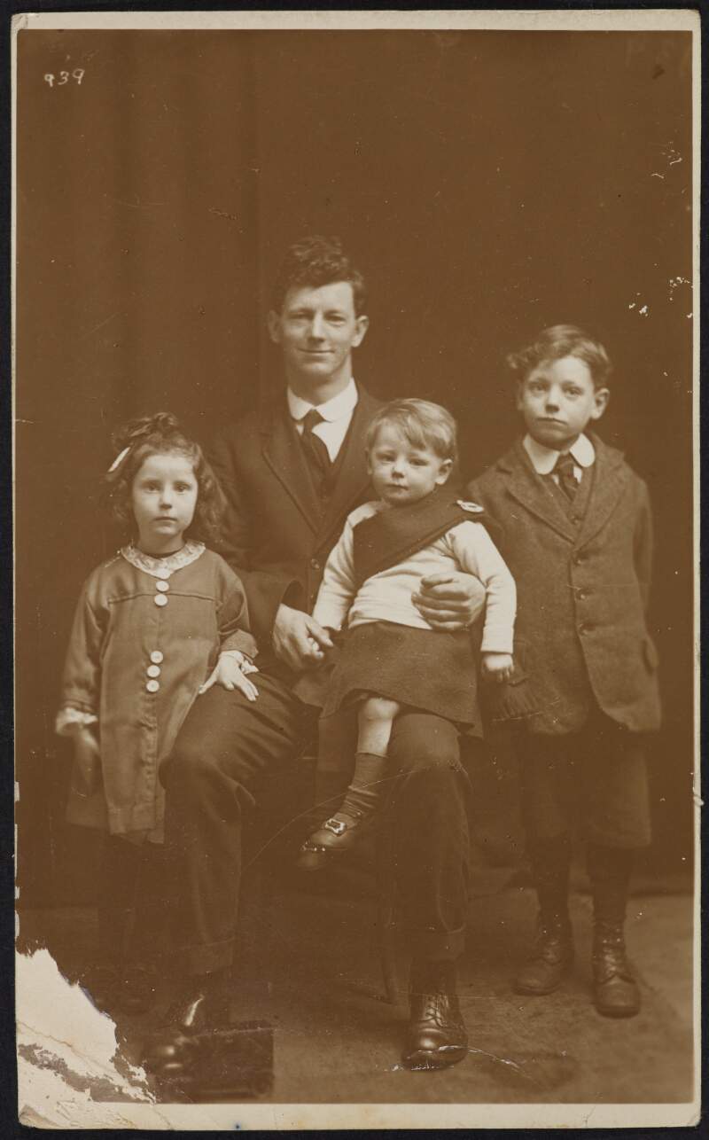 [Unidentified man sitting with young girl, and two young boys]