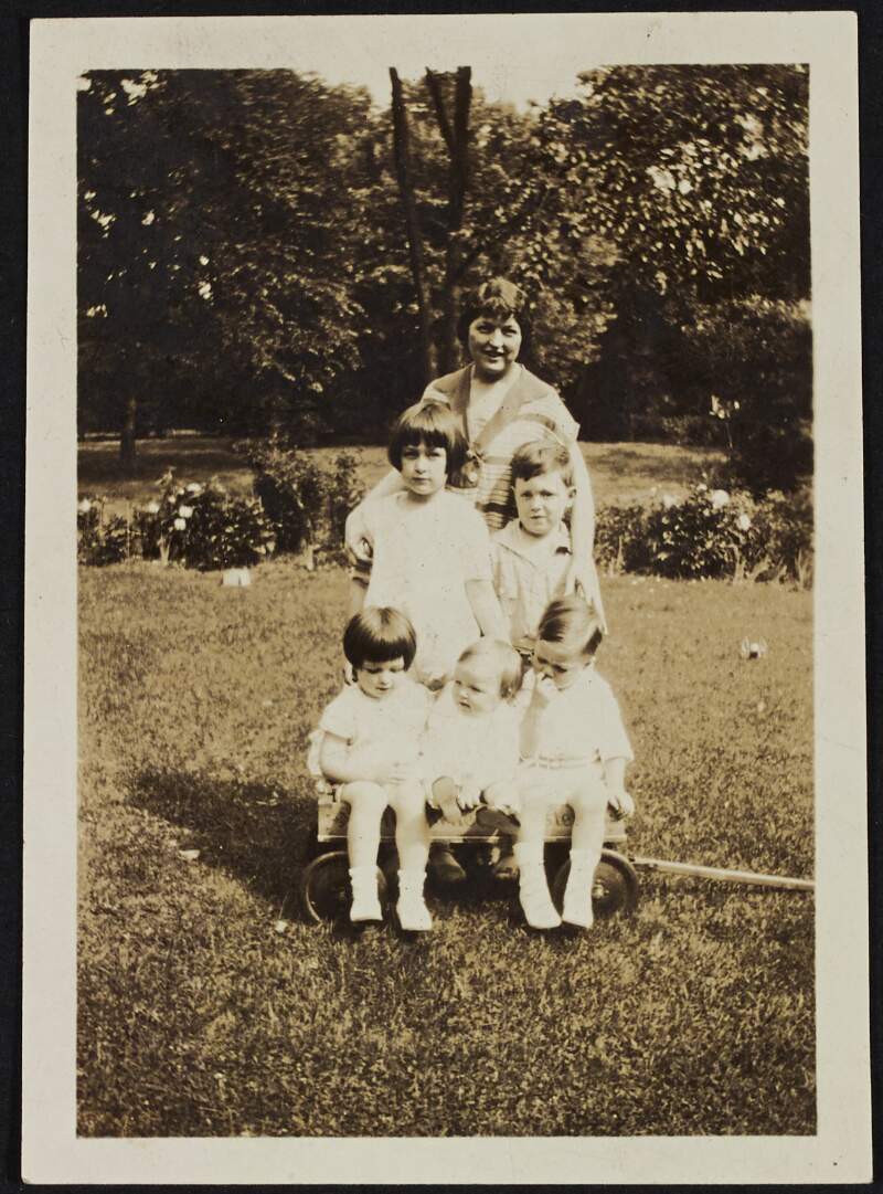 [Five unidentified children and an unidentified woman in a garden]