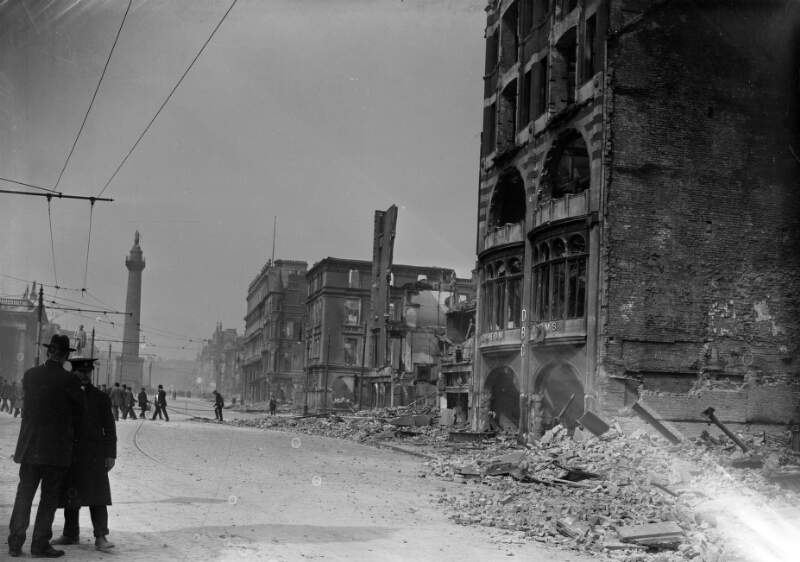 [O'Connell Street, DBC building shelled, Nelson's Pillar, men in foreground]