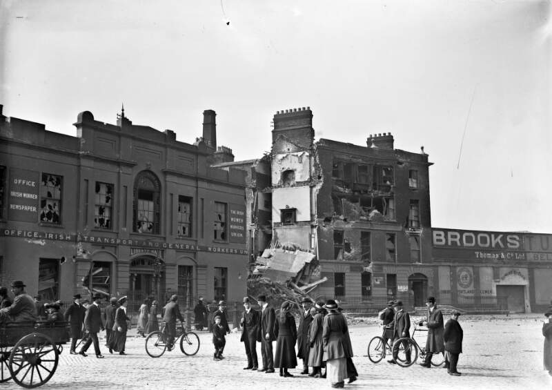 [Beresford Place, showing Liberty Hall and adjacent building named Brooks Cement Store, shelled, people in foreground]