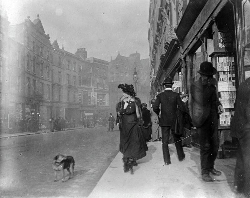[Woman walking with dog on leash past Sibley & Co., stationers, Grafton Street]