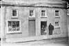 [Street scene, Drumcollogher, Co. Limerick. Woman in shawl and young girl at half door.]
