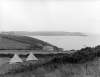 [View of a coastline, dotted with tents and houses, in an unknown location]