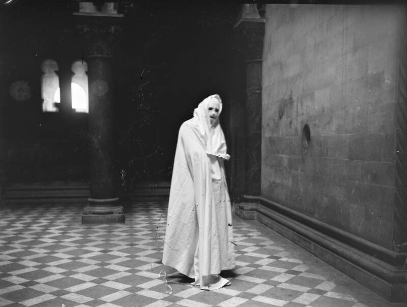 [Swiss 94 B.Oberland. Man shrouded in a cloak standing on a tiled floor in the Museum Building, Trinity College Dublin.]
