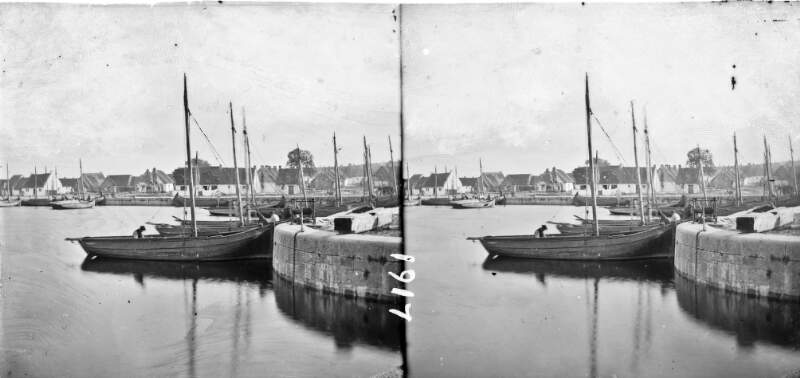Harbour (River Corrib) local sailing boats tied in foreground, thatched houses (Claddagh) in background, Galway City, Co. Galway