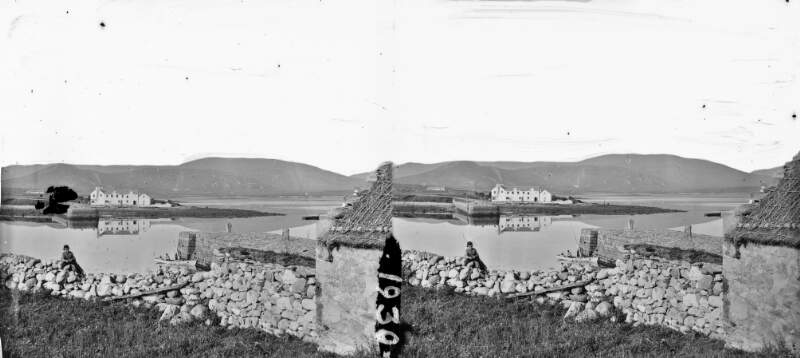 Opposite causeways on river or lake, hills in background, boy on stone wall in foreground, Lough Corrib, Co. Galway