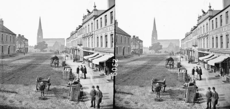 Street scene showing shops, carts and people, with Church of Ireland Parish Church in the background, Lurgan, Co. Armagh
