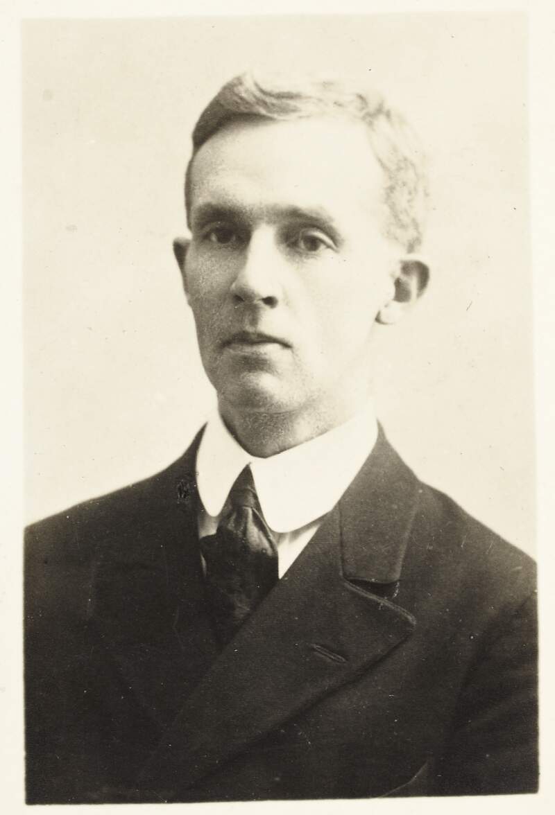 [Head and shoulders, front facing portrait of Erksine Childers, wearing a suit and tie, printed to a postcard]