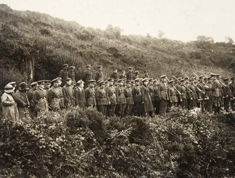 [Soldiers in formation, and men and women, listening to an oration at a mass service for Michael Collins, on roadside at Béal na Bláth, Cork]