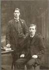 [Bulmer Hobson seated at forefront with Padraig Ó Riain standing behind, front facing, three-quarter length portrait]