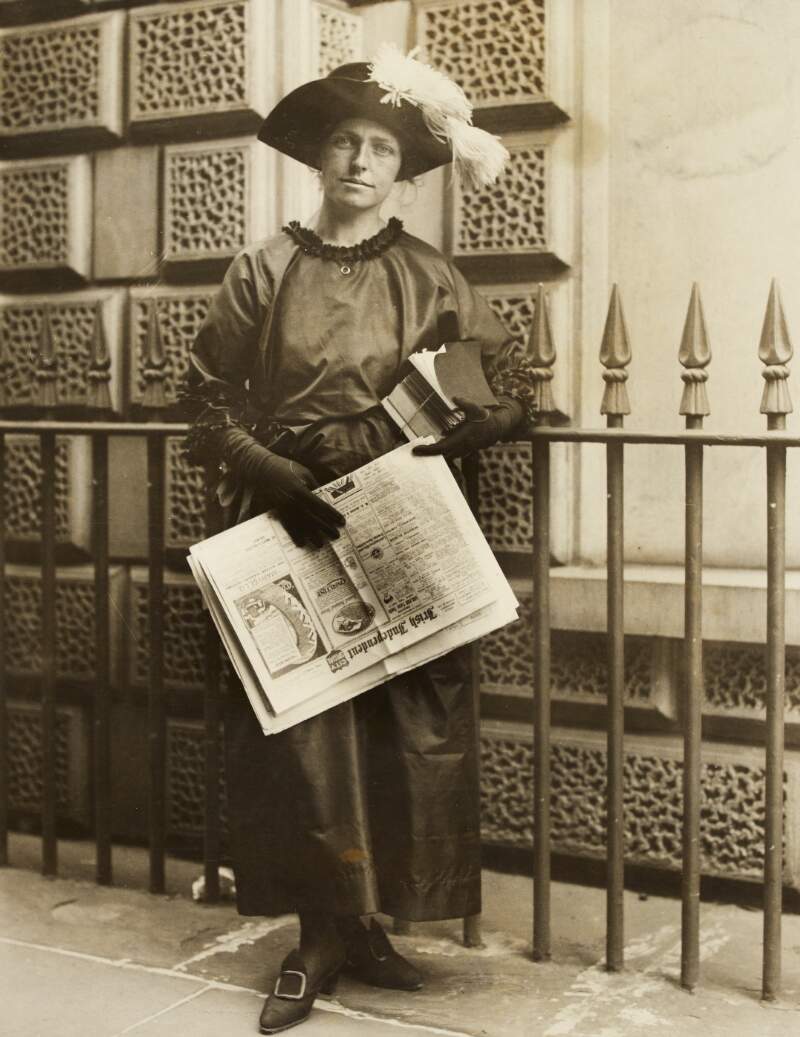 [Full-length, facing front portrait of Muriel MacSwiney, holding books and an 'Irish Independent' newspaper]