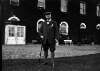 [John Redmond standing on lawn with walking stick, large house in background]