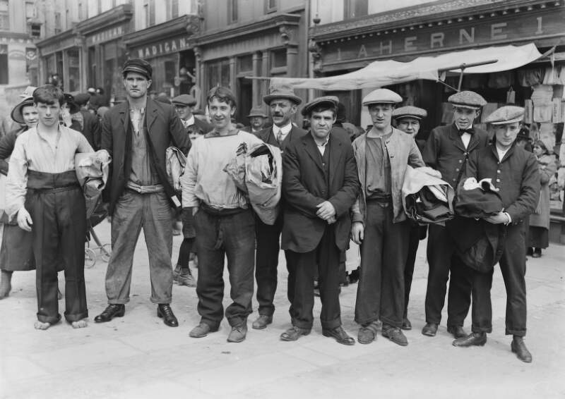 [Survivors of the Lusitania disaster, Cobh, Co. Cork : group of men and crew, standing outside 'Aherne' shopfront]