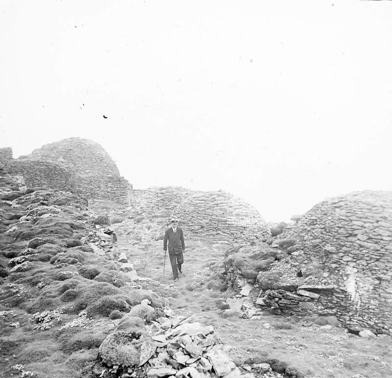 [Commissioner walking past the beehive cells on Skellig Michael (Great Skellig), off the coast of Co. Kerry]