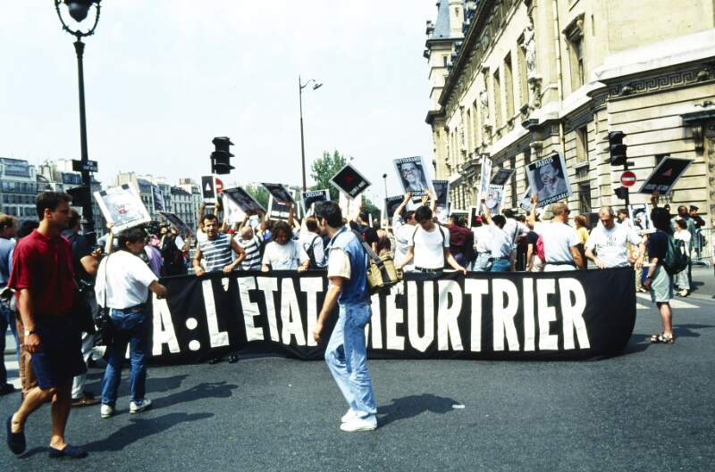 Protesters carrying banner: "SIDA L'ETAT MEURTRIER". International Lesbian and Gay Association Conference: Paris Conference