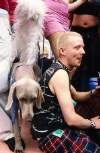 Blond man with shaved head in tartan kilt sitting beside dog. Dublin Lesbian and Gay Pride March
