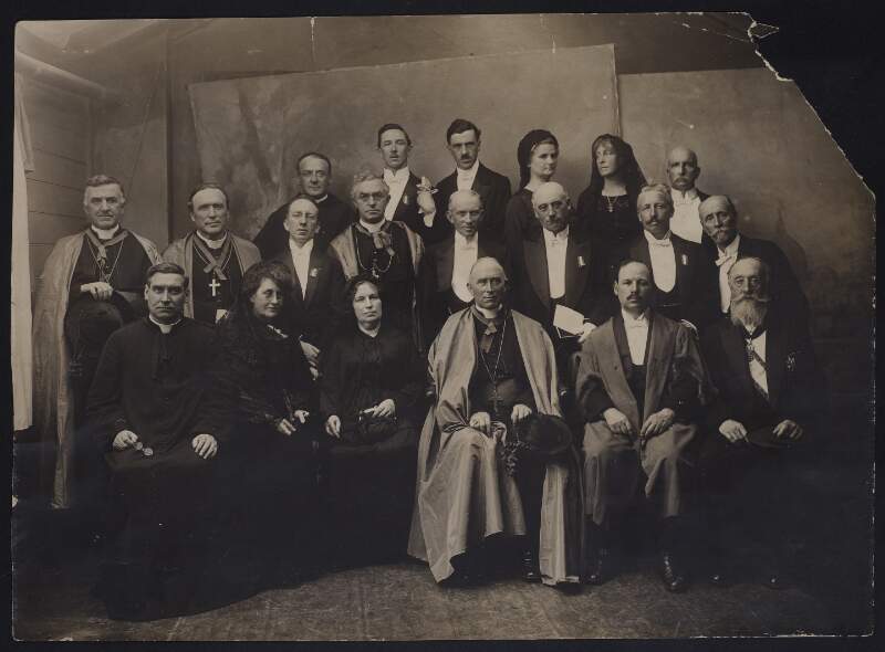 [Group portrait of 16 men and 4 women, Seán T. O'Kelly second row third from the left, Count Plunkett front row first on the right]
